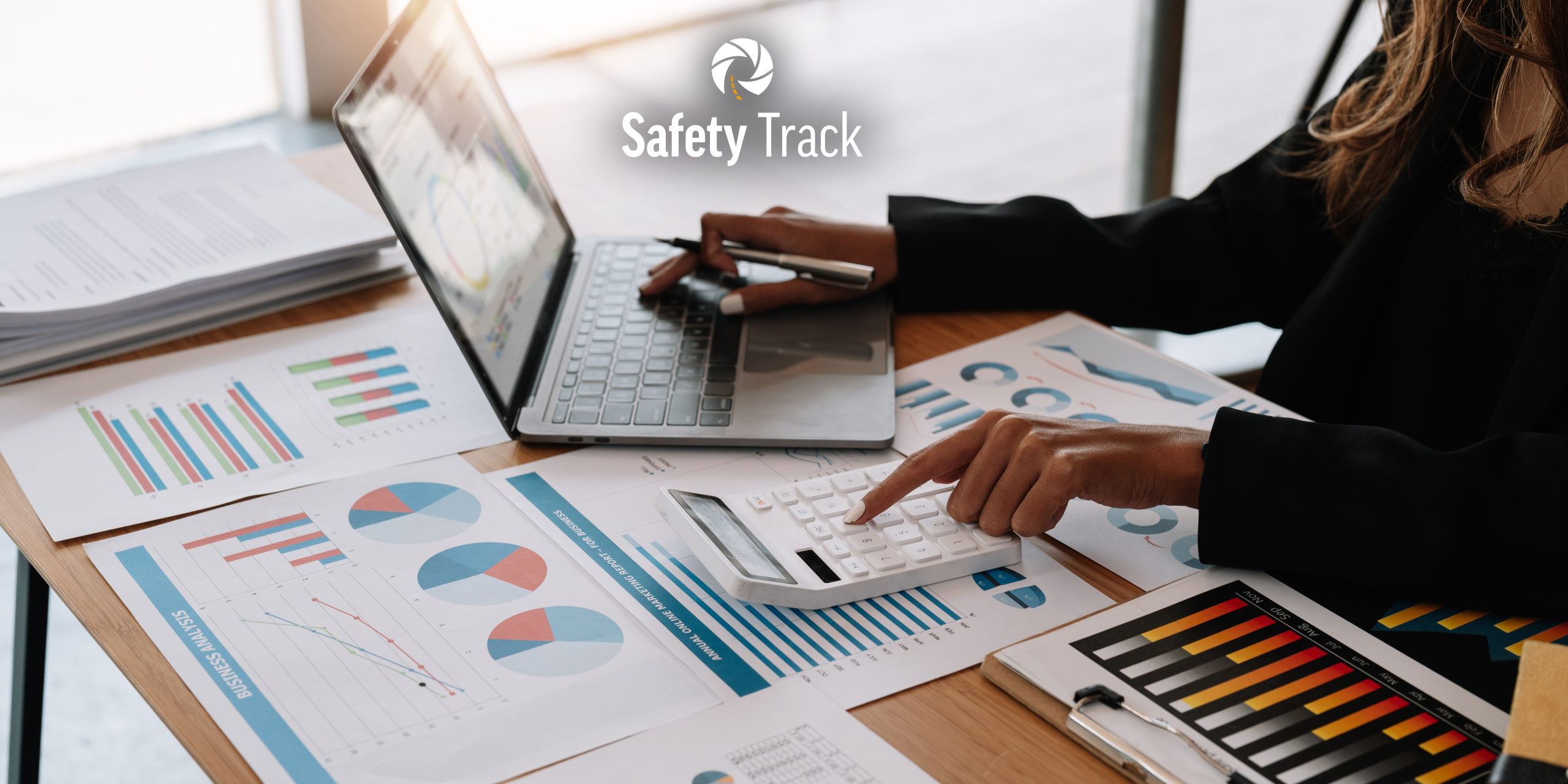 Person analyzing business data with charts and graphs, using a laptop and calculator, highlighting operational efficiency and cost management in fleet telematics.