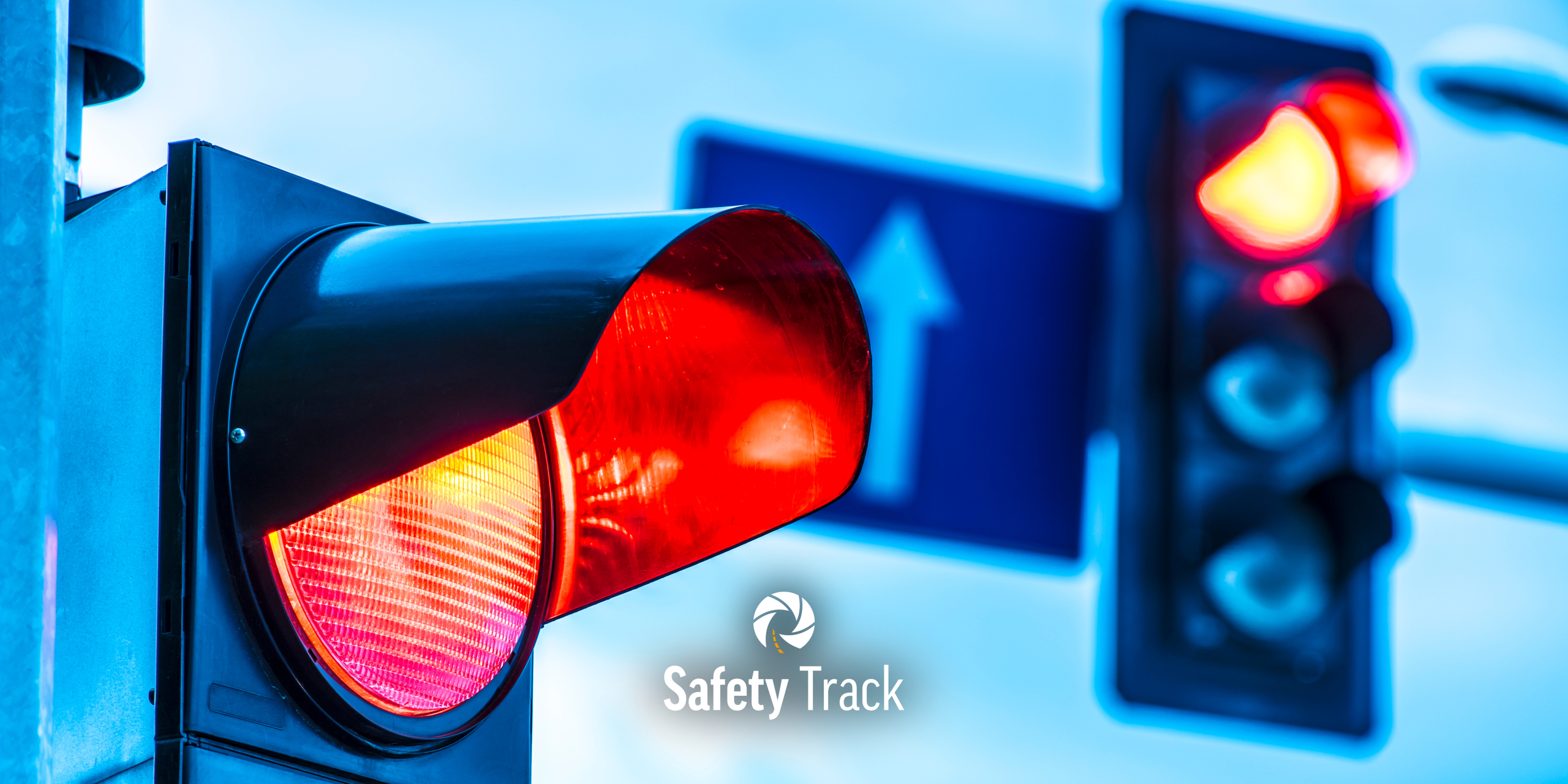 Red traffic light signaling stop with Safety Track logo, emphasizing intersection safety and red light compliance awareness.